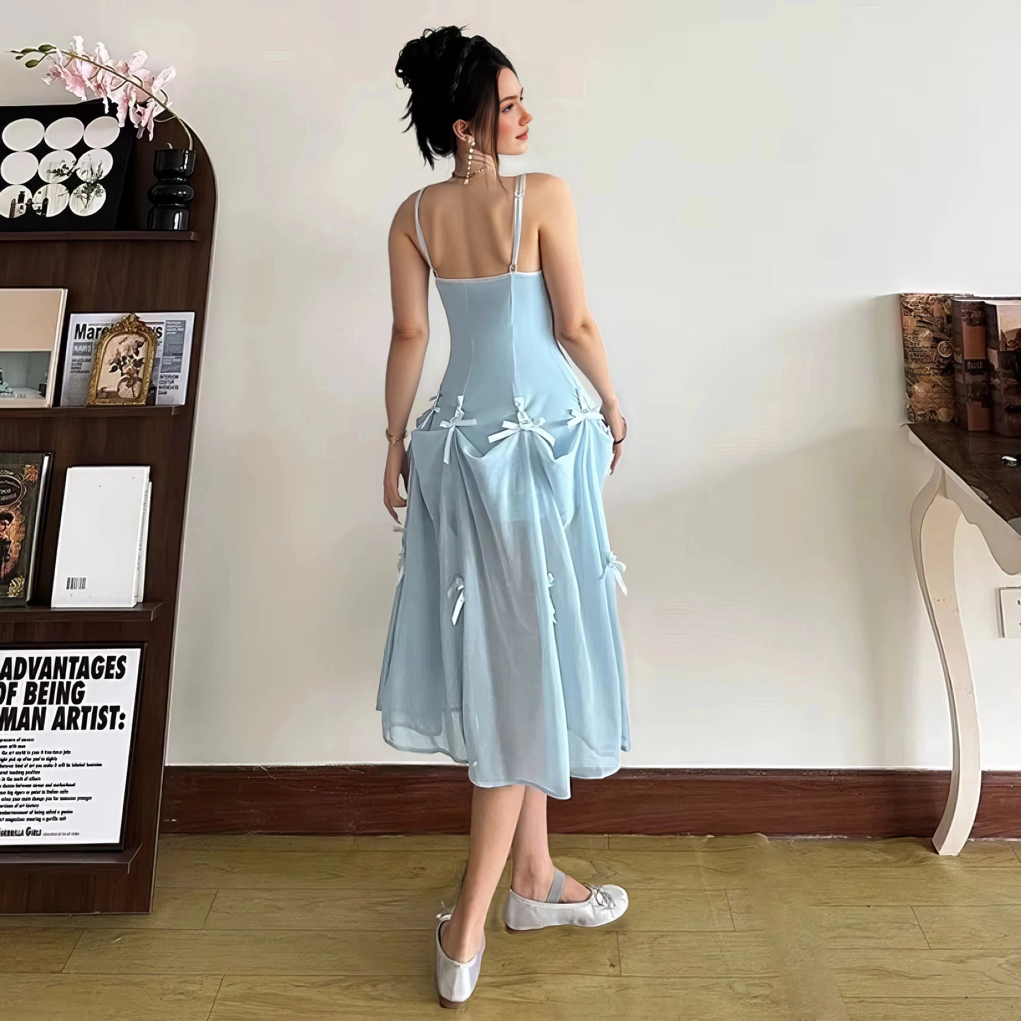 Back view of light blue prom dress with spaghetti straps, open back and bow-detailed flowing skirt